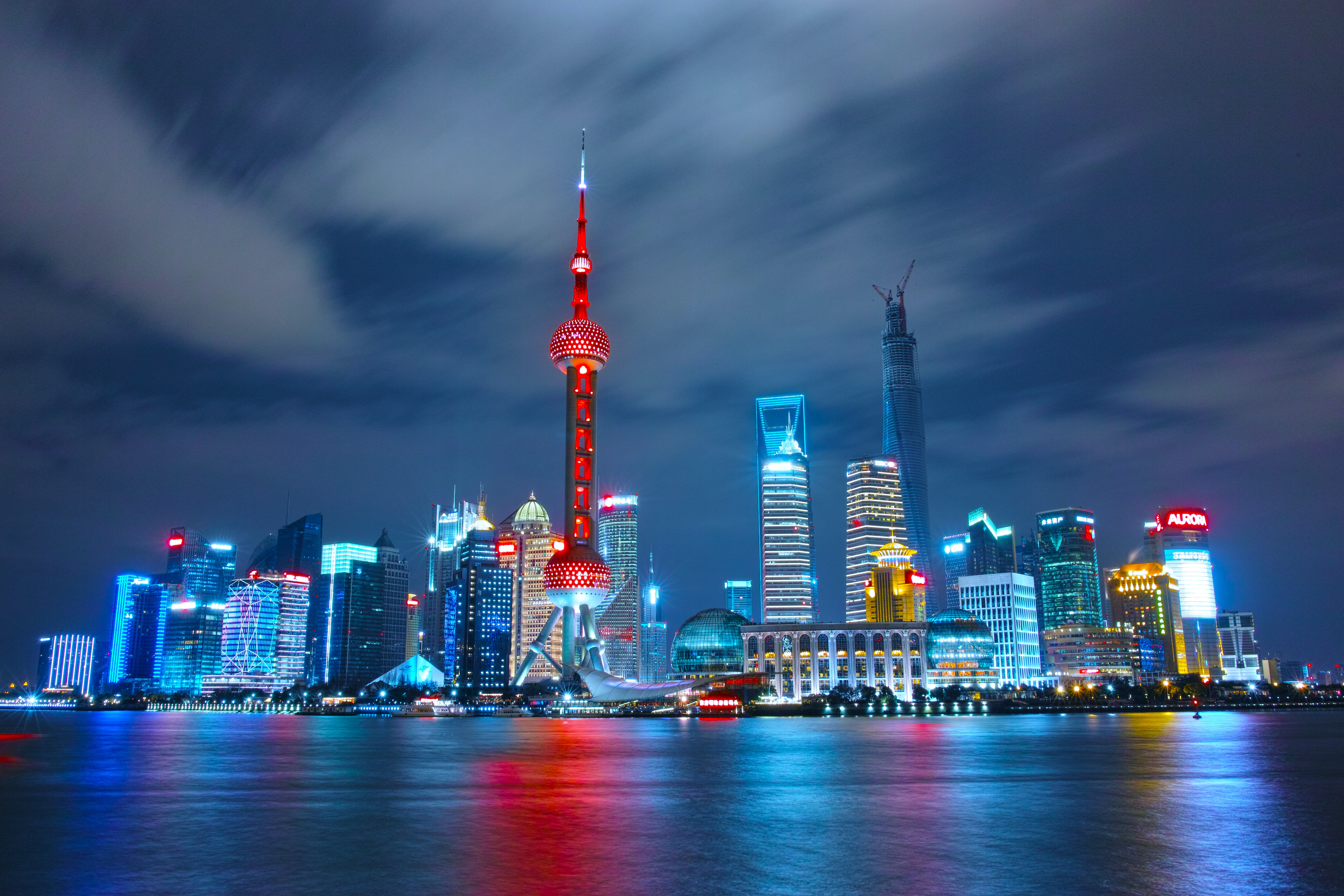 A night time view of a city, from the water.