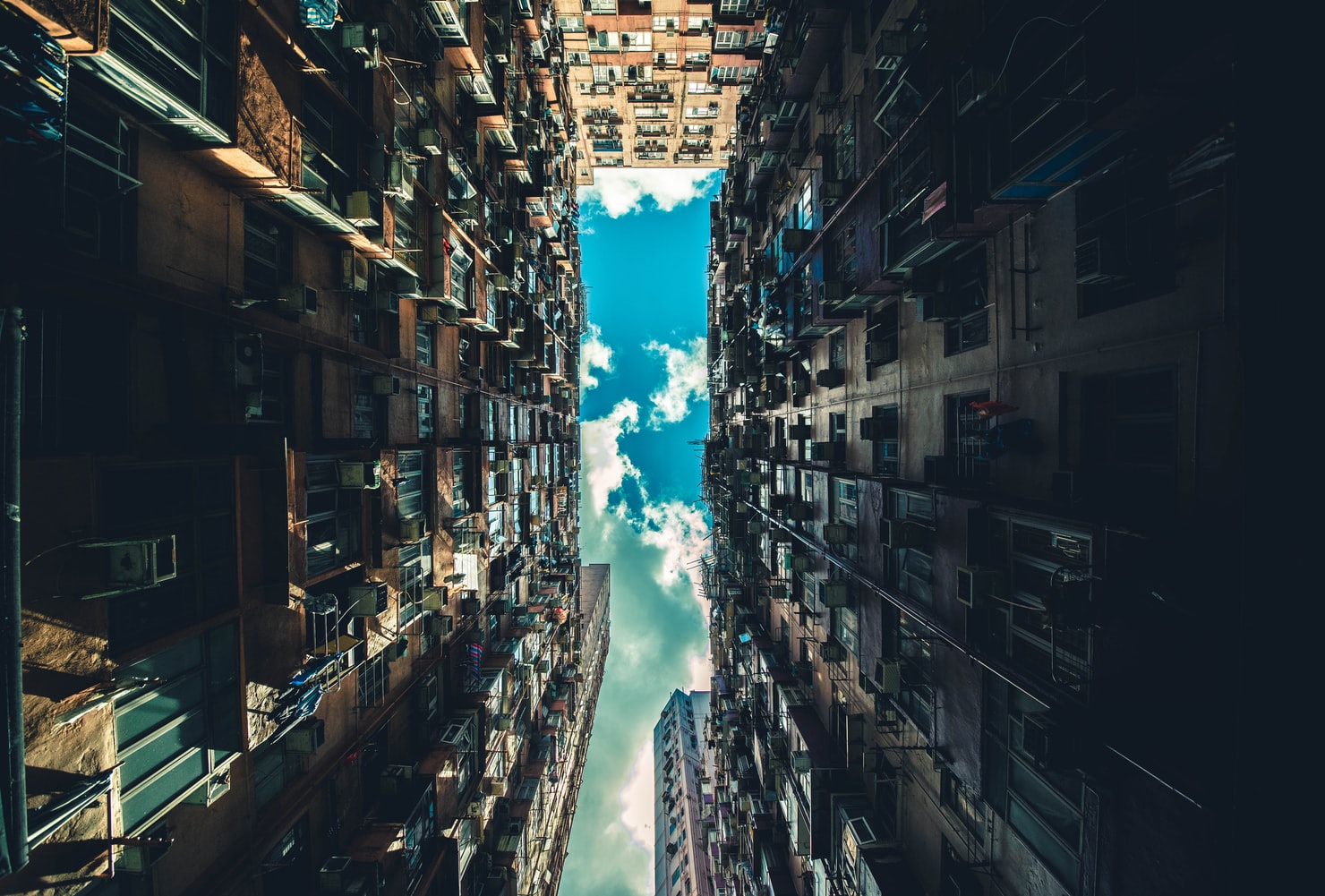 A tight perspective of looking upward towards the sky, while surrounded by buildings on all sides.