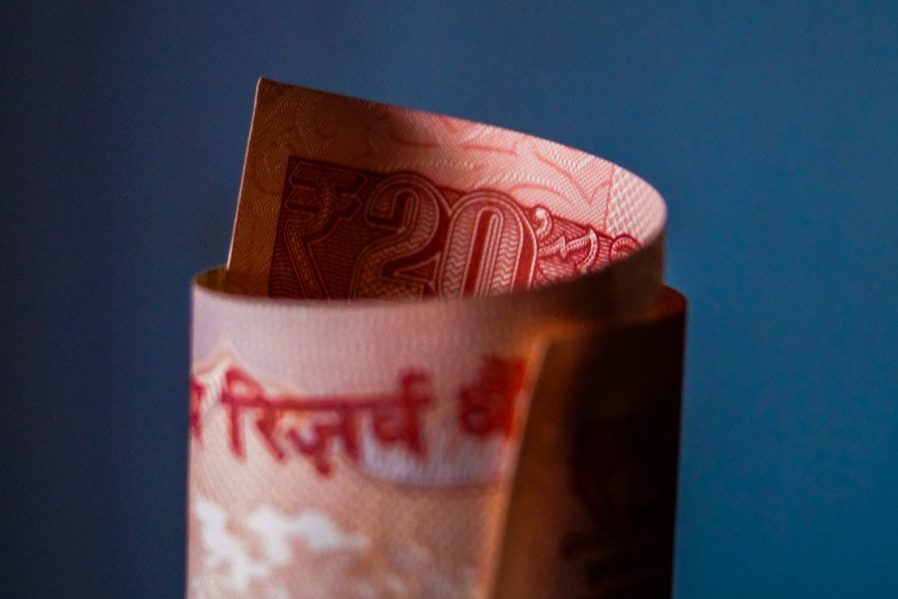 A red bill, in an unknown currency, rolled into a tube, with a blue background.