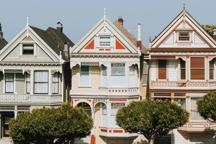Three victorian row houses, on a slope, viewed from the front.