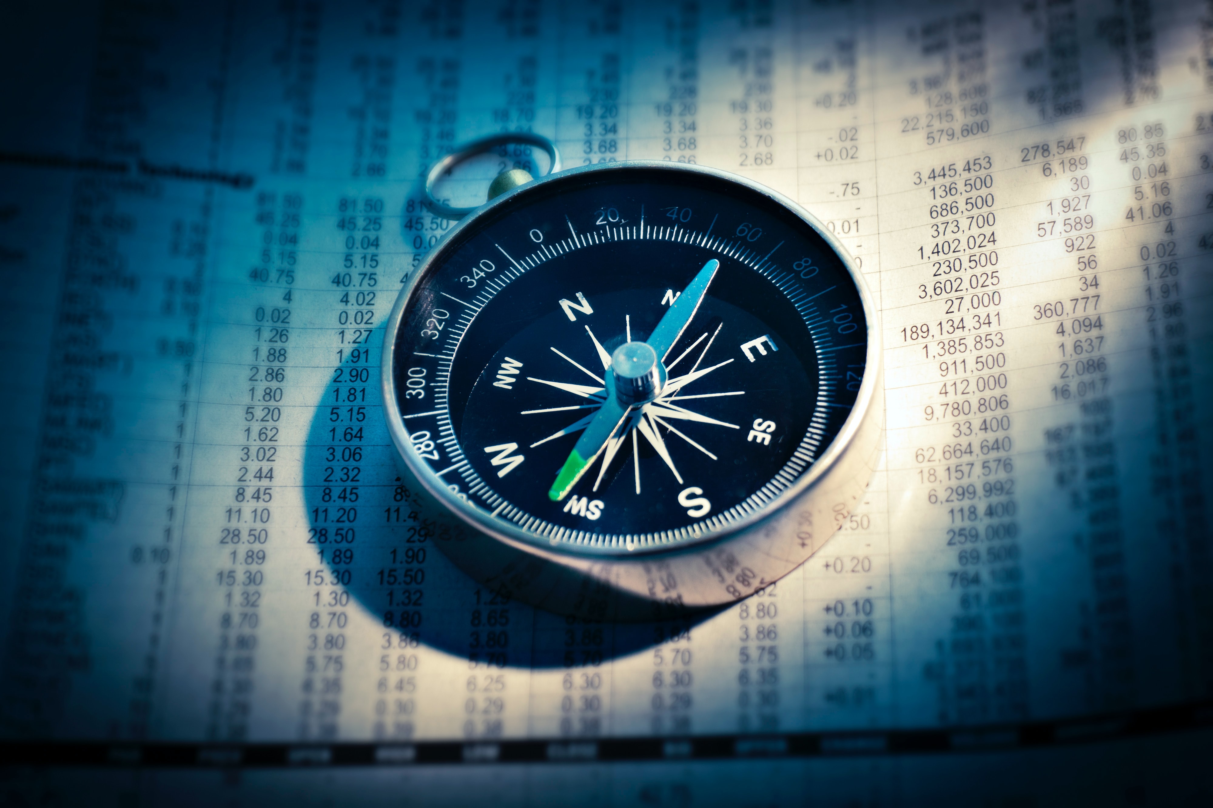 A metal compass sitting on top of a financial report.