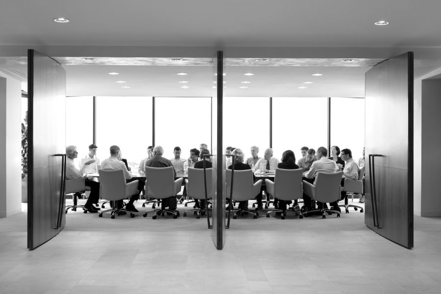 A black and white photograph of the Bailard Conference room, showing a group of people around the table.