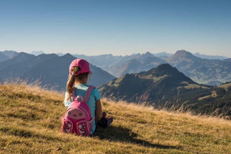 Child in pink hat with pink backpack on mountain